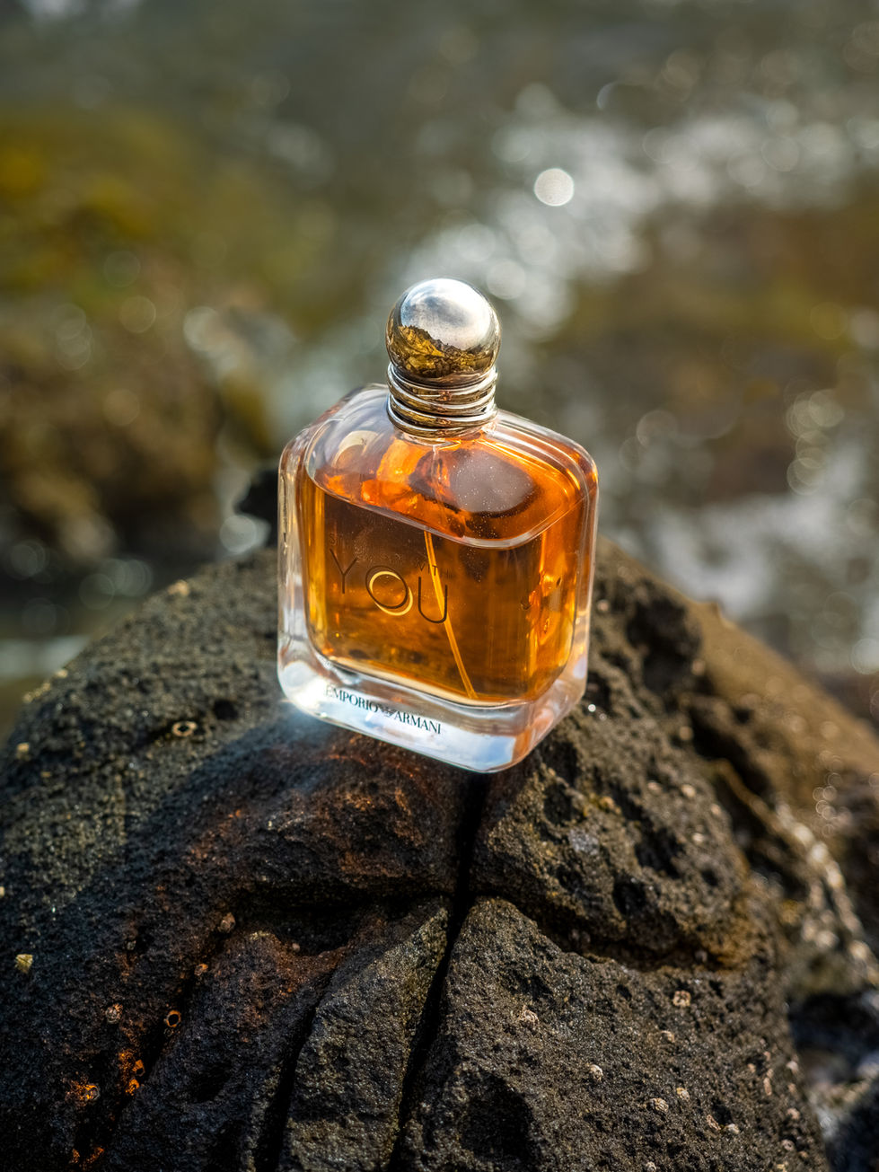 Fotografia commerciale di profumo nell’acqua, flacone immerso con riflessi e luce naturale per branding e advertising