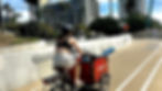 Woman riding a cargo bike up the California incline with a child in the bucket