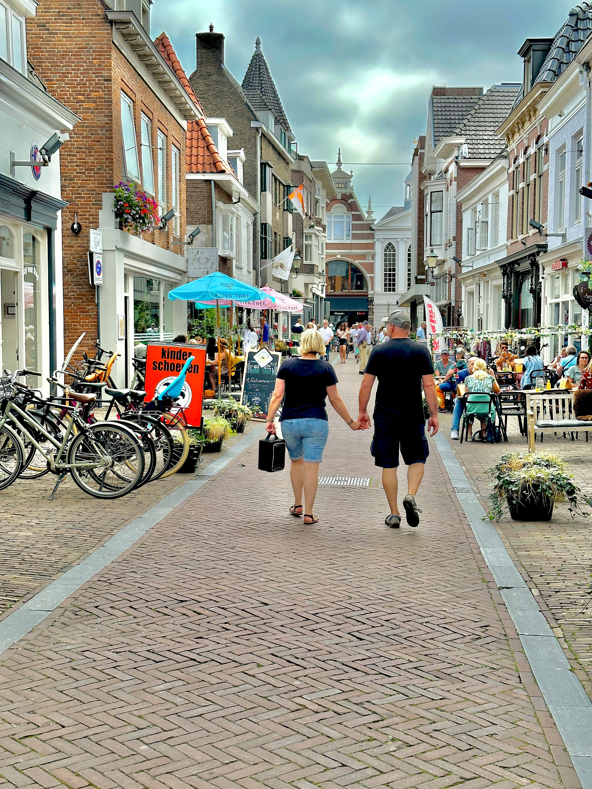 Couple holding hands walking along one of the shopping street in Amersfoort