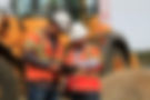Two men in safety gear reviewing a tablet at a worksite