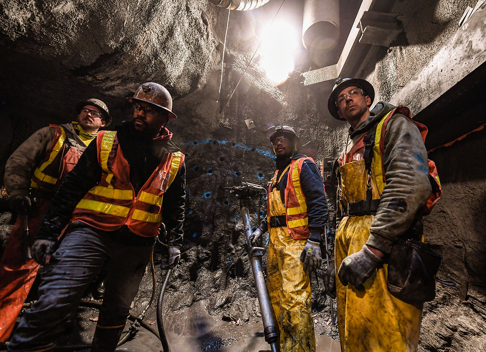 Four workers in hard hats and safety vests underground
