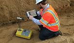Construction worker testing soil with tablet