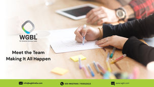 Hands writing on paper at a wooden table with colorful pens and tablet. WGBL logo and text: Meet the Team Making It All Happen.