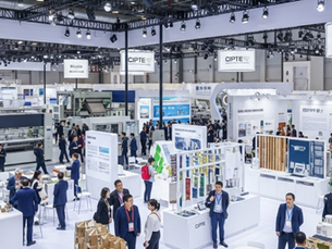 Busy trade show with people in suits interacting at white booths displaying various products. Overhead signs read "CIPTE." Bright lighting.