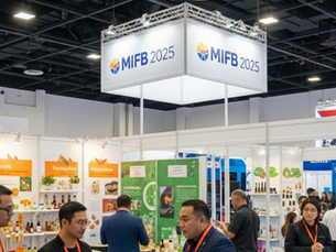 People interacting at MIFB 2025 trade show, surrounded by vibrant booths with products and signage. Ceiling lights illuminate the event space.