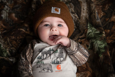 Photo of a baby dressed in camo with a carhartt beanie
