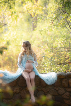 pregnant woman cradles belly in light blue open front gown