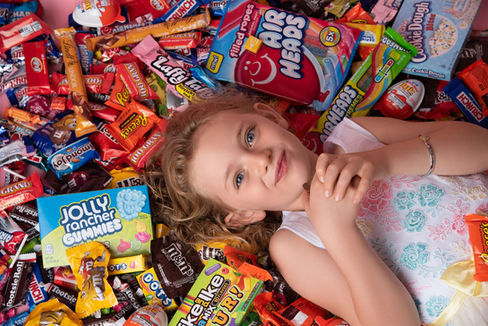 Photo of a little girl laying on a pile of candy