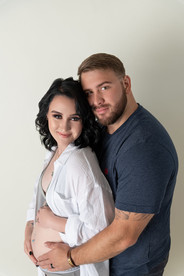 tattooed pregnant woman in underwear holds her belly with her partner