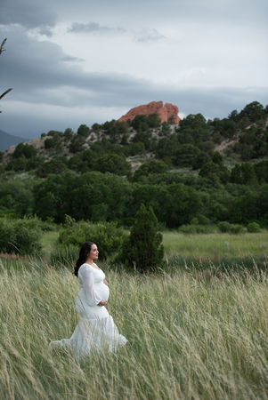 summer maternity photo in white gown in the middle of field of tall grass