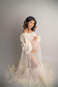 pregnant woman poses in sheer mesh white gown