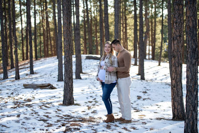 snowy winter maternity photo in forest in casual clothing