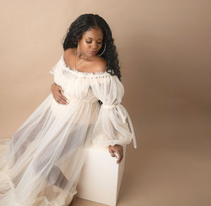 pregnant woman poses in studio in white gauze gown