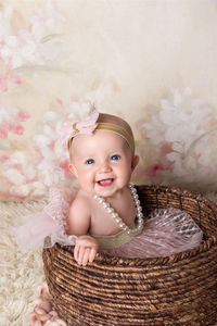 Baby girl wearing a tutu and pearls against a floral backdrop