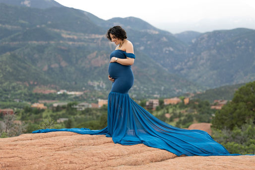 pregnant woman in blue dress cradles bump