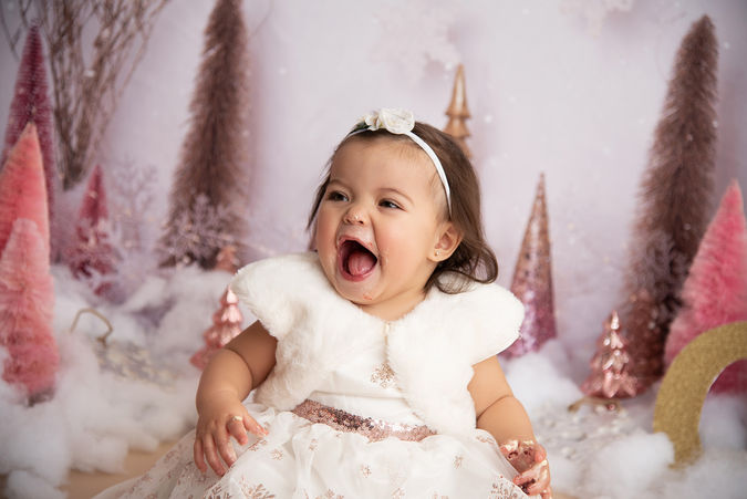 Little girl dressed in white in front of pink and purple bottle brush trees