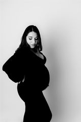 black and white photo of a pregnant woman in black gown showing off baby bump