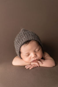newborn photo of a baby boy resting his chin on his hands and sleeping