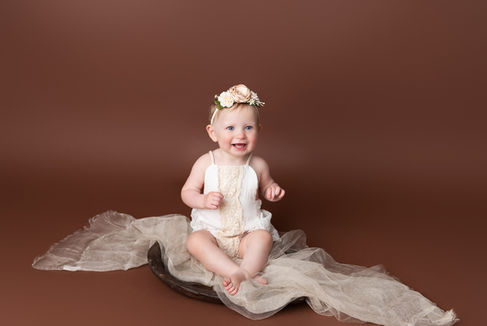 Little girl dressed in white on a brown backdrop
