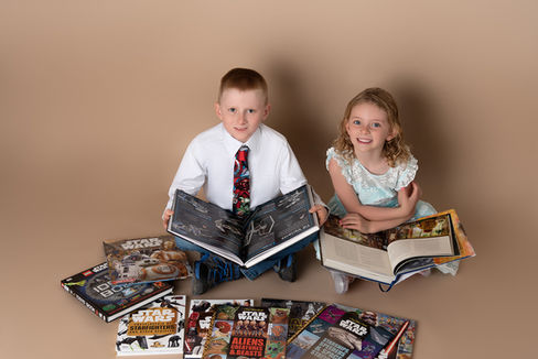 Brother and sister sitting down with books across their laps
