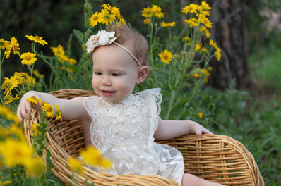 Photo of a little girl picking yellow flowers from a wicker chair