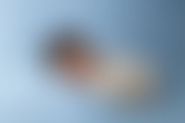 newborn baby boy in ivory pjs sleeps against light blue backdrop