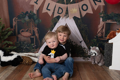 Photo of two little brothers in front of a tent with forest animals stuffies