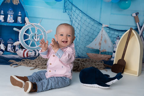 Little boy dressed in a pink nautical shirt in front of a nautical background