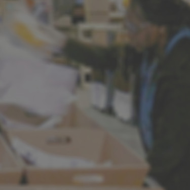 pack line employee placing material into boxes on conveyer line, warehouse setting
