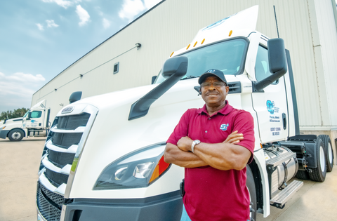 Smiling truck driver by white "Freight Transportation" semi-truck.