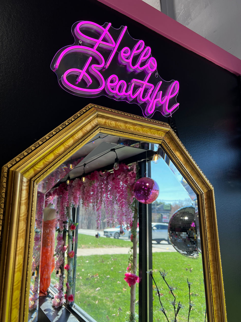 Pink neon sign reading Hello Beautiful above a gold mirror