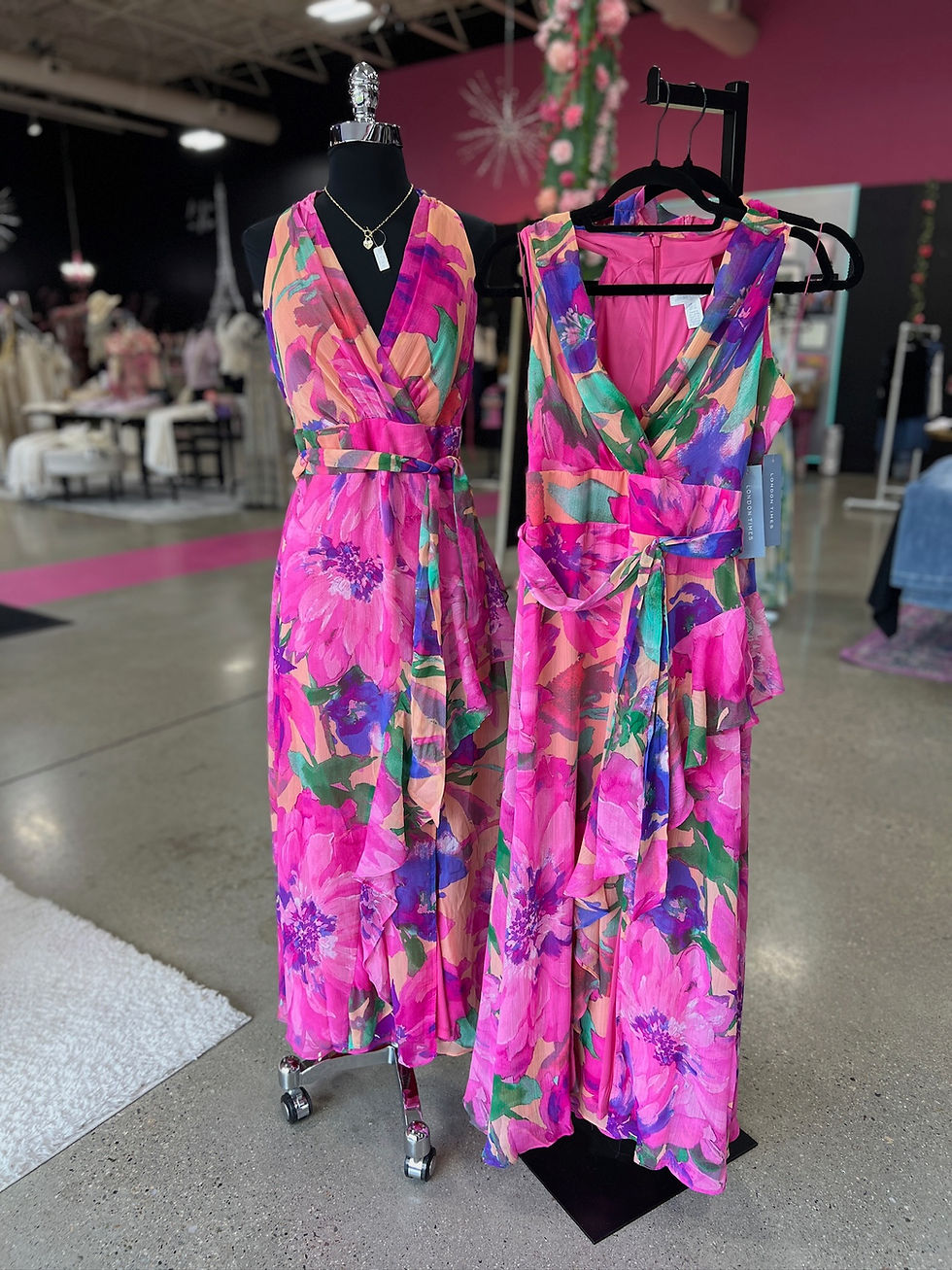 Vibrant pink floral maxi dresses on display in a boutique.