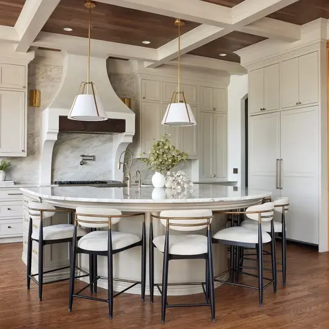 Modern kitchen remodel with a large oval island, marble countertops, pendant lights, wooden floor, and custom cabinetry.
