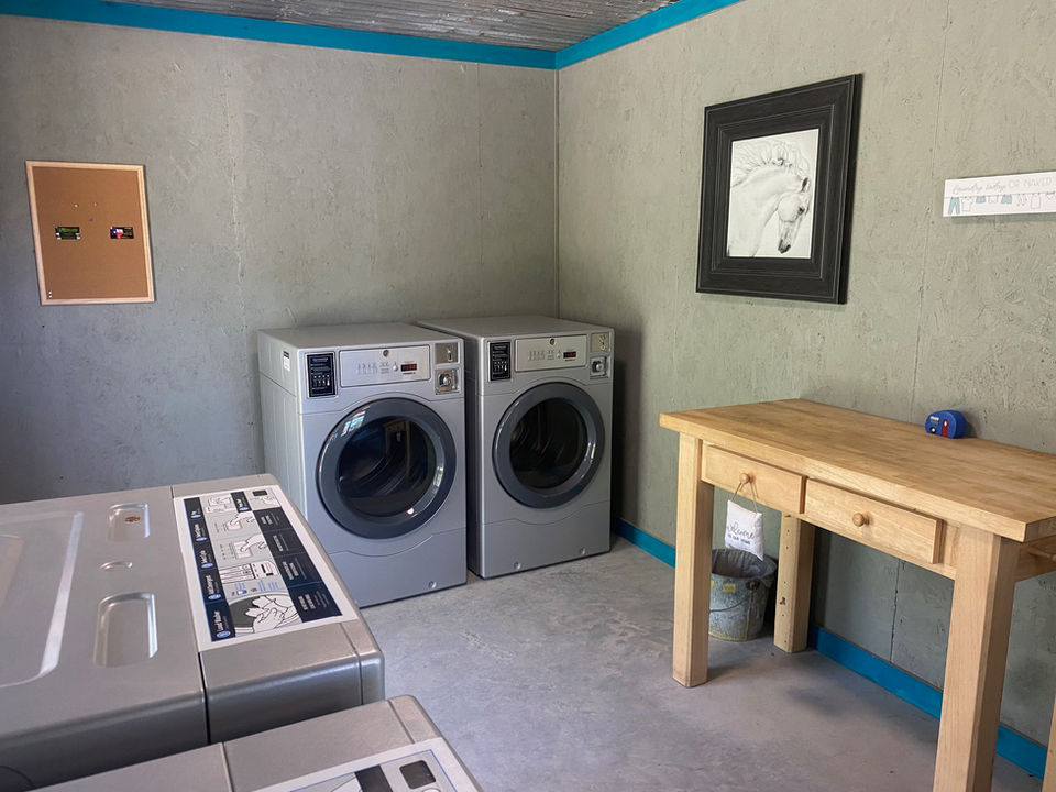Two washing machines and a table inside a laundry room setting.
