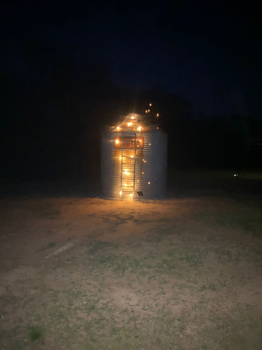 Silo structure at night, lights inside, dark background, outdoor setting.