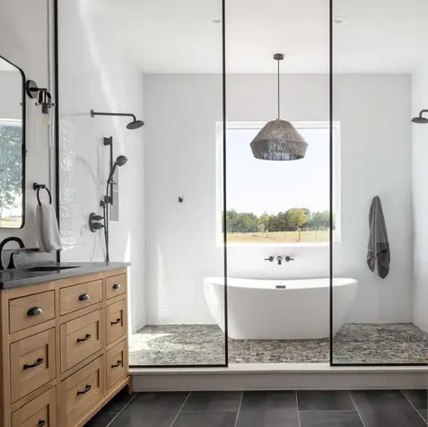 Modern bathroom, ideal for home renovations, features a freestanding tub, large mirrors, wooden vanity with dual sinks.