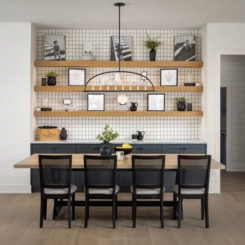 Dining area featuring a wooden table, six black chairs, and shelves with framed art—ideal for post-renovation reflections.