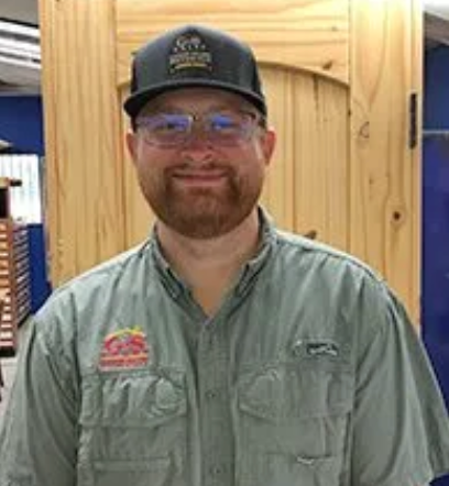 Smiling man in glasses, cap, and collared shirt