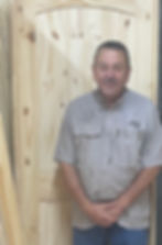 Man in a collared shirt standing by a wooden door