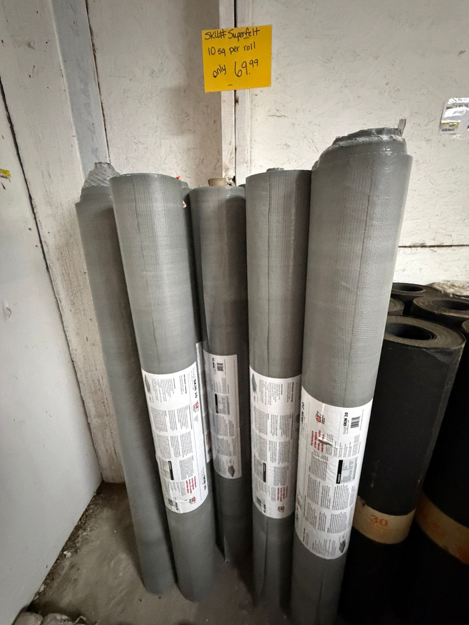 Rolls of grey roofing underlayment in a warehouse storage