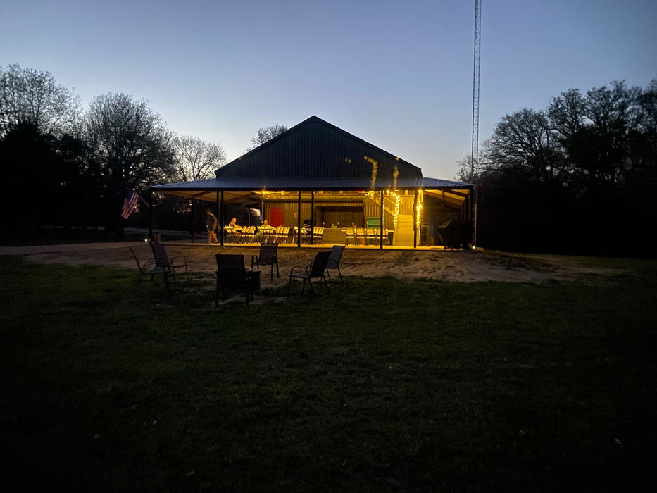 Exterior shot of a lighted building with chairs in the foreground at dusk.