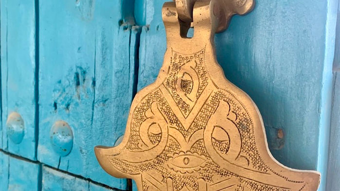 blue wood doors, brass hamsa hand, decorative detail, brass decoration