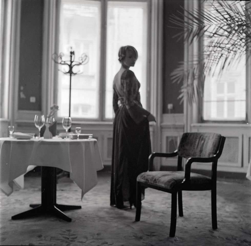 Дівчина в вечірній сукні стоїть зі столом у ресторані Hotel George