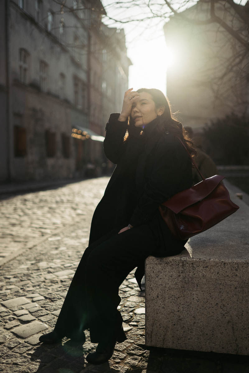 Дівчина в чорному з бордовою сумкою та чорними окулярами