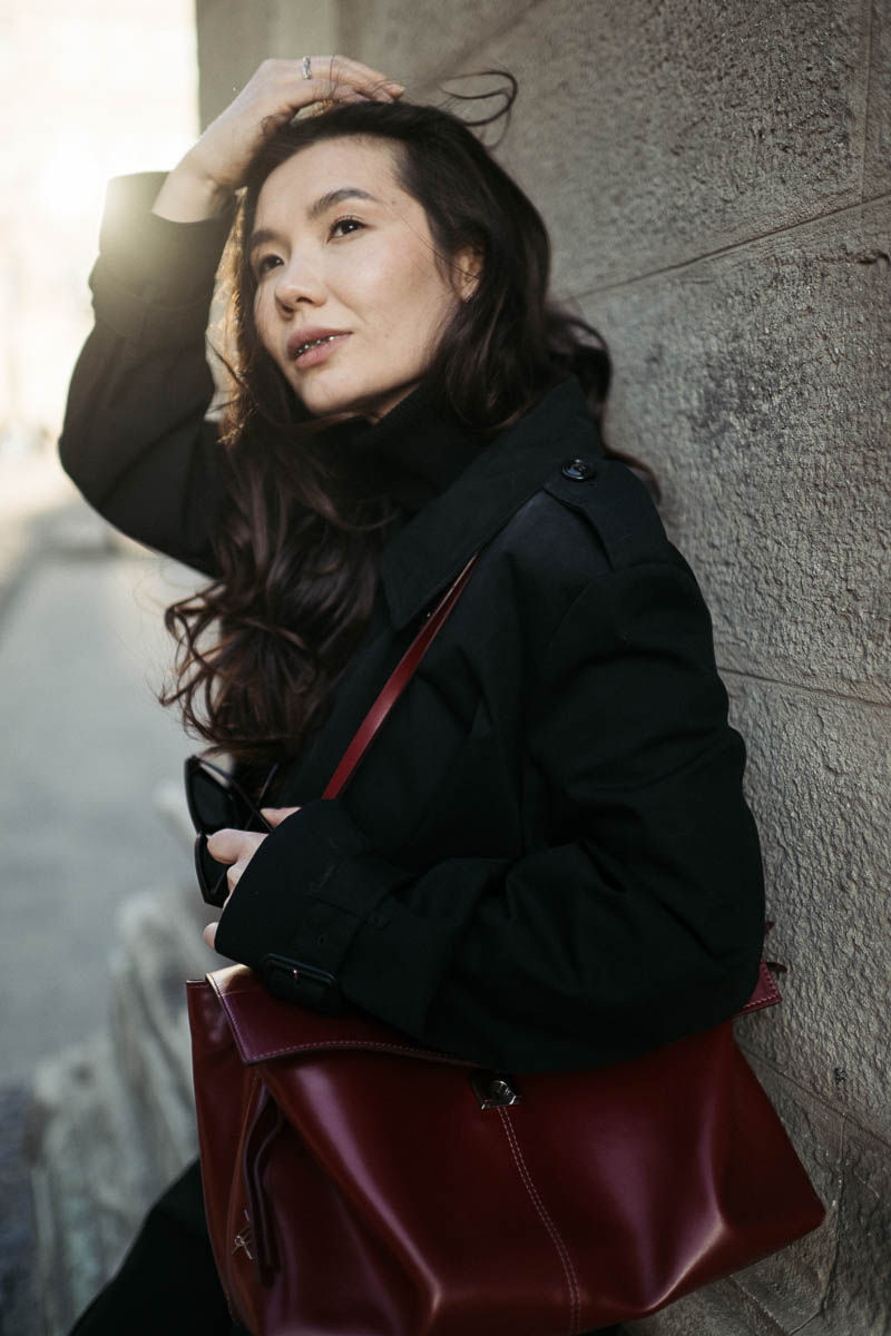 Дівчина в чорному з бордовою сумкою та чорними окулярами