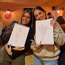 two people holding up drawings of a bird and smiling