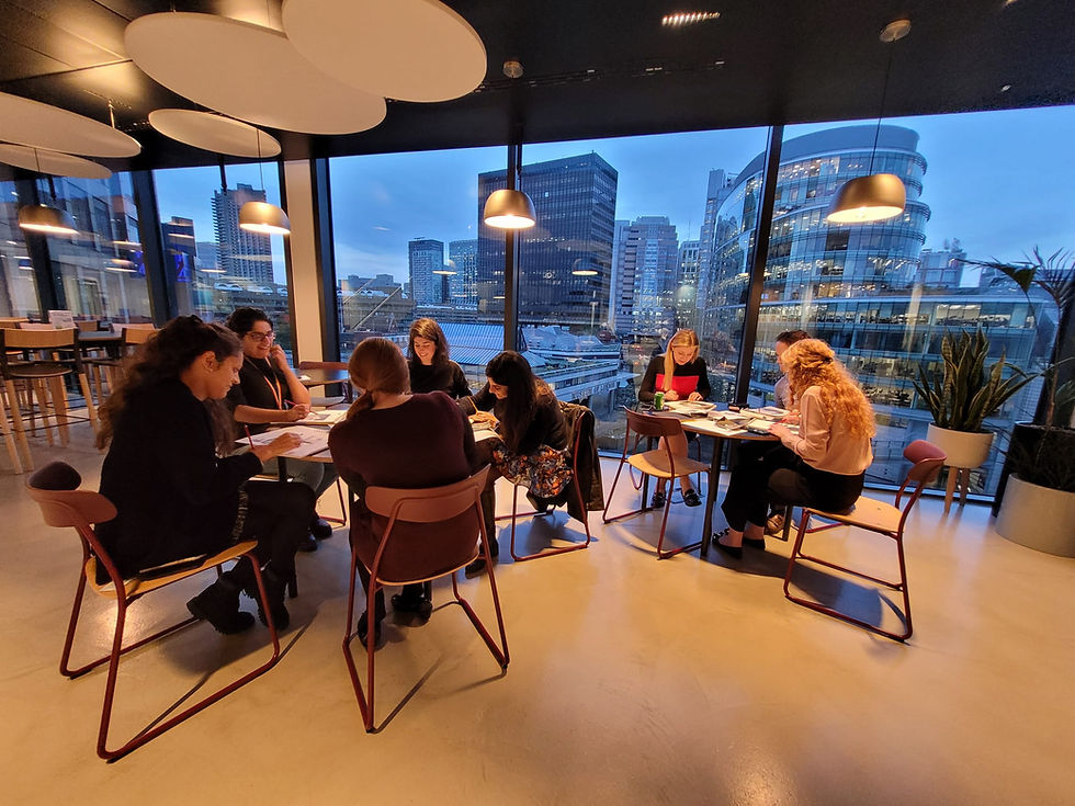Group Of Employee's in a corporate workshop drawing on paper. View of london city from the office.