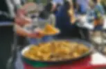 Un adhérent fait le service d’une paella géante lors du repas de l’association ouvert au public et en extérieur