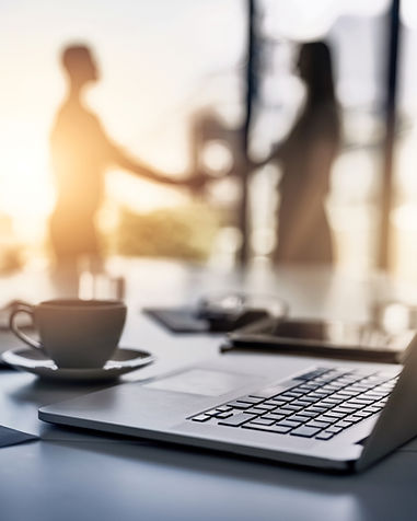 making-smart-business-moves-closeup-shot-laptop-desk-with-businesspeople-shaking-hands-bac