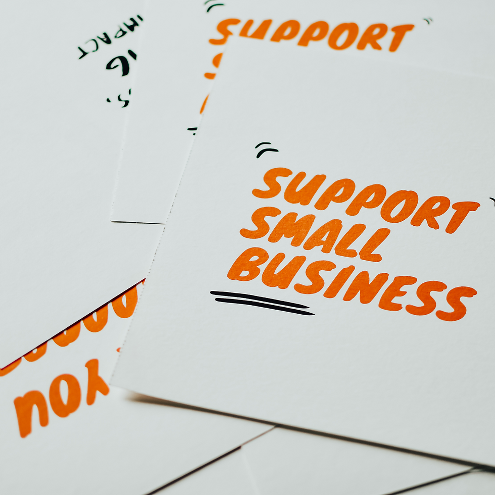 Signs with "Support Small Business" in bold orange text with black accents are scattered on a flat surface, creating a motivational vibe.